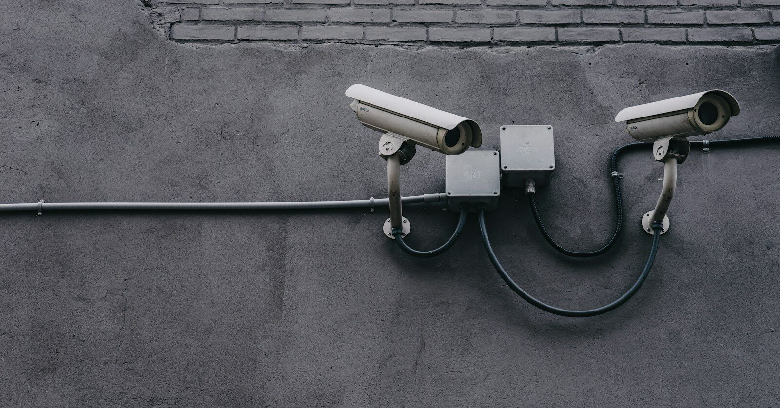 two bullet surveillance cameras attached on wall